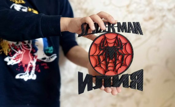 Детска декорация с логото на Спайдърмен, съчетано с червен паяк и изписано име.