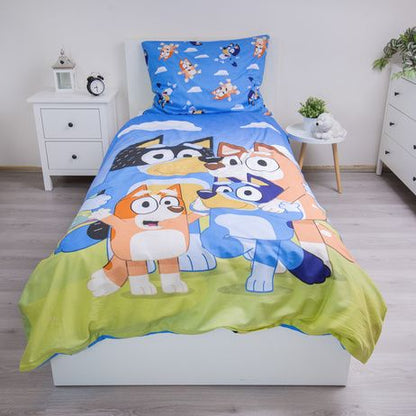 Детско двулицево спално бельо Bluey с героите Блуи и Бинго на фона на зелена трева.