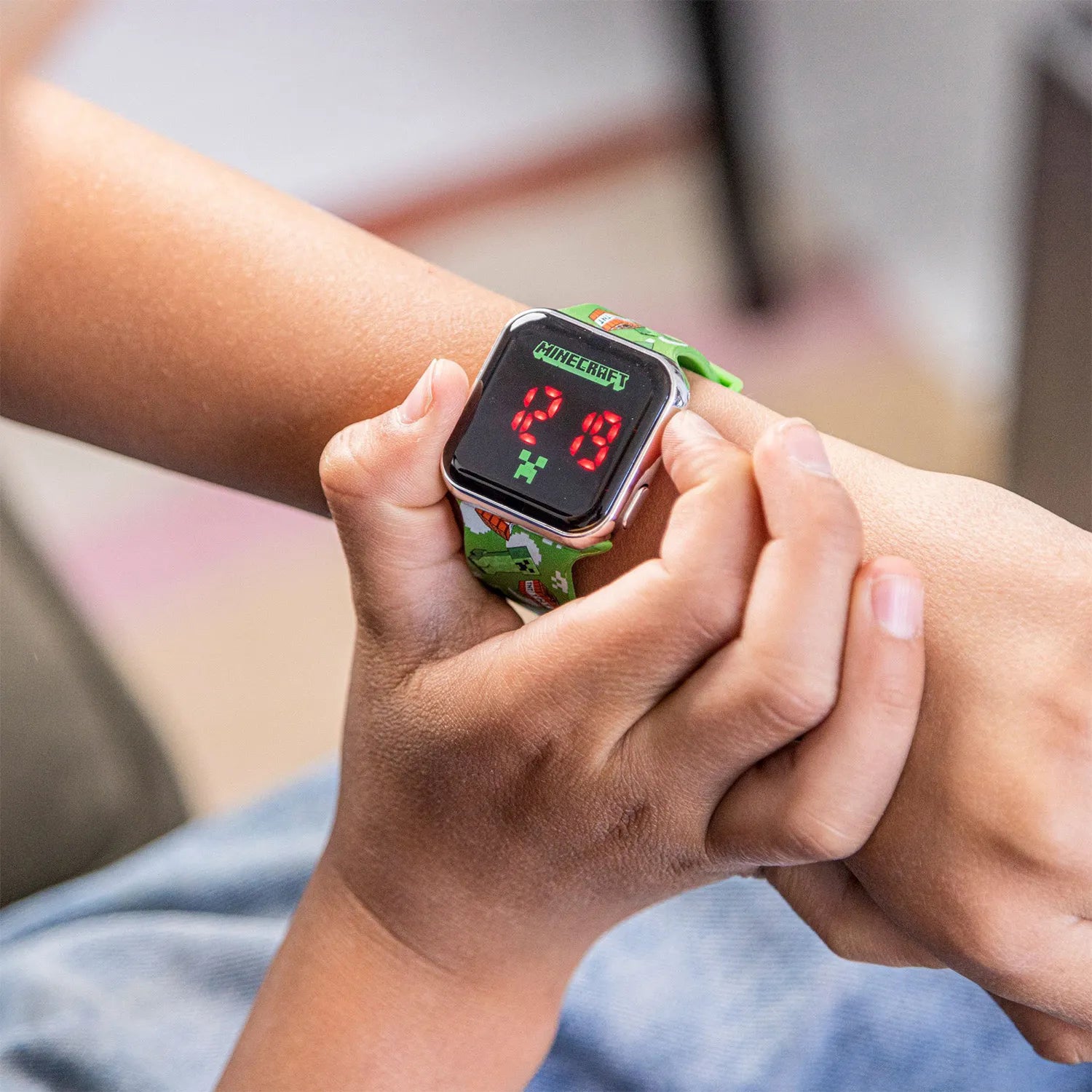 Детски часовник с дигитален дисплей на ръката, зелен каиш с мотиви, подходящ за деца.